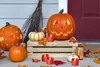 Halloween decorations on a porch, including carved pumpkins, smaller pumpkins, a broom, and LED tea lights. Produktbild-Vorschau