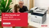 A man and a child are looking at a printer on a desk, with a red overlay on the left side of the image containing promotional text. Produktbild-Vorschau