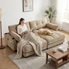 A woman is reading a book on a sectional sofa with a dog sleeping on it. A coffee table is in the foreground. Produktbild-Vorschau