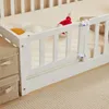 A close-up view of a white wooden bed rail with two small white latches. Two storage boxes are stacked to the left of the bed rail. A stuffed fox and a cloud-shaped pillow are on the bed. Náhľad obrázku produktu