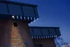 Icicle lights are installed on the roof of a brick house at dusk. Produktbild-Vorschau