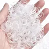 A hand holding a pile of small, transparent hair ties. Anteprima dell’immagine prodotto