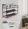 A black metal wine rack mounted on a white wall, displaying wine bottles and glassware. Decorative items are on the top shelf. Náhled obrázku produktu