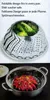 A foldable steamer basket filled with broccoli and another steamer basket with crawfish inside a pot. Produktbild-Vorschau