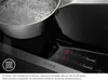A close-up of an induction cooktop with a pot of boiling water. Produktbild-Vorschau