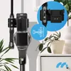 A cordless vacuum cleaner is mounted on a wall bracket, with a close-up inset showing the bracket and a screw being inserted into a wall. A small potted plant is on a white cabinet in the foreground. Podgląd zdjęcia produktu