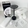 The image shows a black LED table lamp, its packaging box, and protective foam inserts, along with a user manual and a USB charging cable, all arranged on a light gray surface. Produktbild-Vorschau