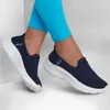 A pair of navy blue Skechers Slip-Ins GO WALK Flex shoes are shown on a person's feet, worn with bright blue leggings. Produktbild-Vorschau