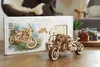 A wooden model motorcycle with a sidecar is displayed in front of its packaging box, with some small jars in the background. Anteprima dell’immagine prodotto