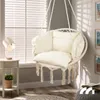 A cozy corner with a hanging chair, a side table with a lamp and plant, and a book on a pouf. Produktbild-Vorschau