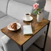 A side table with a croissant, coffee, and a book next to a sofa. Produktbild-Vorschau