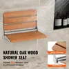 A wooden shower seat mounted on a tiled wall, with water spraying in the background. Anteprima dell’immagine prodotto