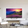 A modern living room with a TV displaying a scenic landscape, a white armchair, and a coffee table with books and mugs. Náhled obrázku produktu
