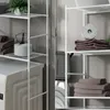 A split image showing two sides of a white metal shelving unit in a laundry room setting. The left side shows a washing machine with a plant and a jar of powder on the shelves. The right side shows towels and a roll of toilet paper on the shelves. Náhled obrázku produktu