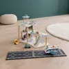 A wooden toy airport playset with vehicles and accessories on a wooden floor. Voir les images du produit