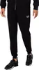 A person wearing a black tracksuit and sneakers, shown from the waist down against a white background. Produktbild-Vorschau