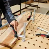 A person is using clamps to hold a piece of wood on a workbench. Náhľad obrázku produktu