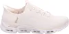 A side view of a single beige Skechers slip-on shoe against a white background. Produktbild-Vorschau