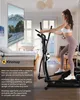 A woman is using an elliptical trainer in a living room setting, with a large screen displaying a scenic view. Anteprima dell’immagine prodotto