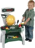A young boy stands next to a toy Bosch work bench, holding a toy saw. Produktbild-Vorschau