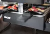 Nahaufnahme eines ausziehbaren Raclette-Grills von Unold auf einer Küchenarbeitsplatte, mit mit Teig Produktbild-Vorschau