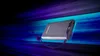 A power bank is shown against a dynamic, abstract background with streaks of blue and purple light. Voir les images du produit