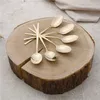 A set of gold spoons arranged on a wooden log. Anteprima dell’immagine prodotto
