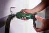 A person is using a cordless rotary cutter to cut into a wall, with a vacuum hose attached to collect dust. Produktbild-Vorschau