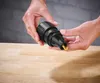 Hands holding a black tool attachment with a gold tip over a wooden surface. Produktbild-Vorschau