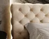 A close-up view of a tufted beige headboard and a pillow. Náhled obrázku produktu