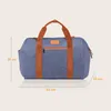 A blue duffel bag with brown straps is shown against a plain light beige background. Dimensions are indicated by lines and text. Náhľad obrázku produktu