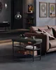 A modern living room with a brown leather sofa, a black shoe bench, and decorative items. Produktbild-Vorschau