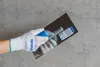A hand wearing a white glove is holding a trowel against a concrete wall. Náhled obrázku produktu