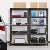 A garage or storage area with shelving units filled with various items, including boxes, bottles, tools, and car parts. A car is partially visible on the left side. Podgląd zdjęcia produktu
