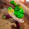 A Hulk action figure in a dynamic pose on a sandy, rocky terrain with dust and debris flying. Náhľad obrázku produktu