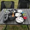 Camping cookware set laid out on a table outdoors, with chairs in the background. Produktbild-Vorschau