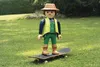 A large toy figure of a gardener standing on a skateboard on a grassy lawn. Náhľad obrázku produktu
