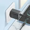 A black Hoco GaN 45W charger is plugged into a white wall socket and charging a smartphone. Produktbild-Vorschau
