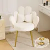 A white armchair with a bow-shaped pillow sits on a rug next to a dresser and part of a vanity table. Podgląd zdjęcia produktu