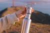 A hand holding a stainless steel water bottle with the Golden Gate Bridge in the background. Podgląd zdjęcia produktu