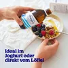A person is pouring omega-3 oil from a bottle into a bowl of yogurt with berries and nuts. Produktbild-Vorschau