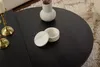 A close-up view of a black round coffee table with decorative items on it. Produktbild-Vorschau