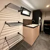 A laundry room with a washing machine, sink, and drying racks. Voir les images du produit