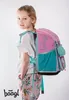 A young girl wearing a backpack and standing against a white background. Náhľad obrázku produktu