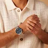 A person wearing a watch and a knitted shirt. Produktbild-Vorschau