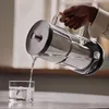 A person is pouring water from a pitcher into a glass. Náhľad obrázku produktu