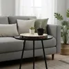 A close-up of a round wooden tray with a black mug and a small plant on a coffee table, placed in front of a sofa. Náhľad obrázku produktu
