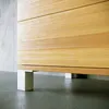 Close-up of the base of a wooden cabinet with white feet. Produktbild-Vorschau