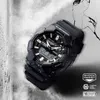A black G-Shock watch is displayed on a cracked, textured surface. Produktbild-Vorschau