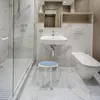 A modern, clean bathroom with a shower, sink, and toilet, featuring a blue and silver shower stool. Náhľad obrázku produktu